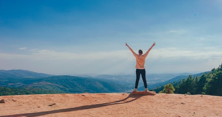 Person in Beige Top on Mountain Cliff